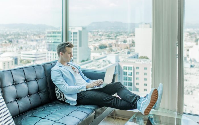 man sitting on sofa while using laptop
