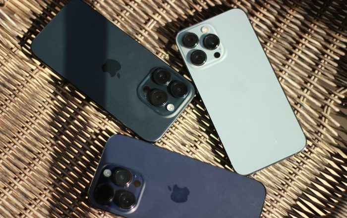 three iphones sitting next to each other on a wicker surface