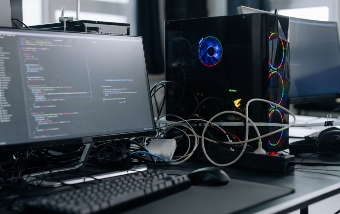 A modern workspace featuring a computer monitor with code, a PC tower, and peripherals.